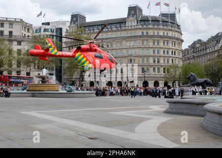 London's Air Ambulance helicopter lands in Trafalgar Square, delivering paramedics to a traffic incident, as crowds look on. Stock Photo