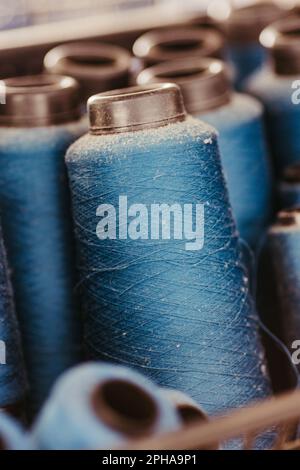 A crisp, vertical shot of multiple blue-colored thread spools, neatly arranged in an orderly fashion Stock Photo