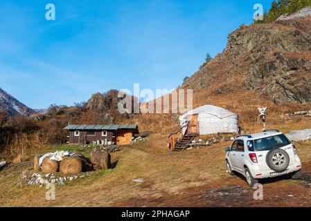 Altai, Russia - October 02, 2022 A Toyota Terios car stands in the mountains with snow next to haystacks and a round house ail in Altai in autumn. Stock Photo
