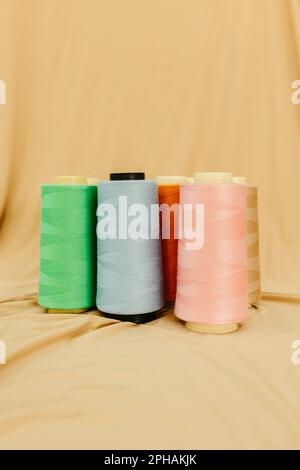 An image featuring an assortment of colorful spools of thread and strings of thread, arranged in a neat, organized pattern on a light background Stock Photo