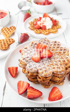 Stacked waffles with strawberry topping on white table Stock Photo