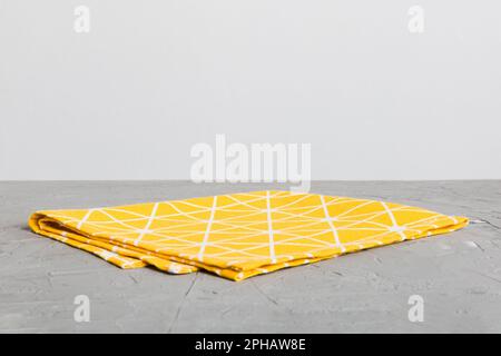 top view with yellow empty kitchen napkin isolated on table background. Folded cloth for mockup with copy space, Flat lay. Minimal style. Stock Photo