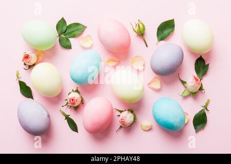 Happy Easter. Easter eggs on colored table with yellow roses. Natural dyed colorful eggs background top view with copy space. Stock Photo