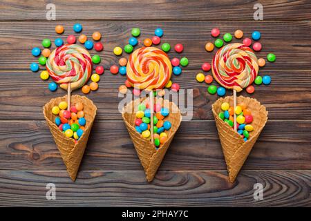 waffle cone full of assorted traditional candies falling out on colored background with copy space. Happy Holidays sale concept. Stock Photo