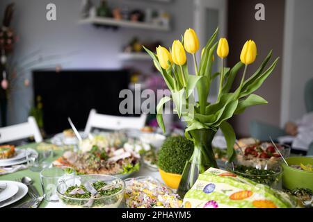 Traditional Easter dishes with white borscht, sausage, eggs, salad and cakes on festive table in Poland. Home interior with easter decor. Spring Stock Photo