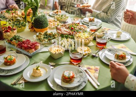 Traditional Easter dishes with white borscht, sausage, eggs, salad and cakes on festive table in Poland. Home interior with easter decor. Spring Stock Photo