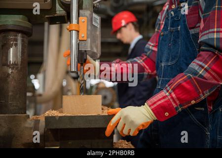Craftman working on a wood solid inside of a factory with his boss beside him Stock Photo