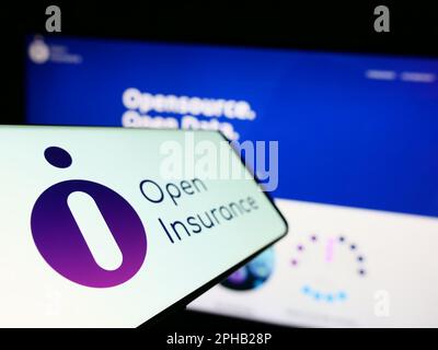 Mobile phone with logo of industry initiative Open Insurance on screen in front of webpage. Focus on left of phone display. Stock Photo