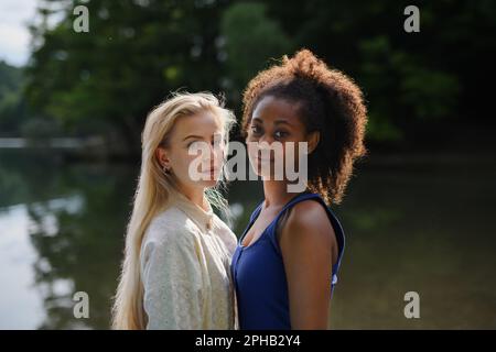 Young women spending time together in nature, near lake, concept of strong, long lasting friendship. Stock Photo