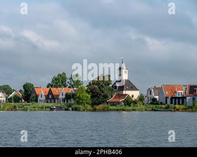 Church and houses on dike of Durgerdam village from Buiten IJ river near Amsterdam, Netherlands Stock Photo
