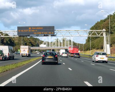 Traffic and overhead gantry displaying electronic information about travel time, motorway A27 between Utrecht and Hilversum, Netherlands Stock Photo