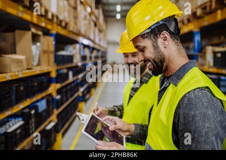Warehouse workers checking stuff in warehouse with digital system in tablet. Stock Photo