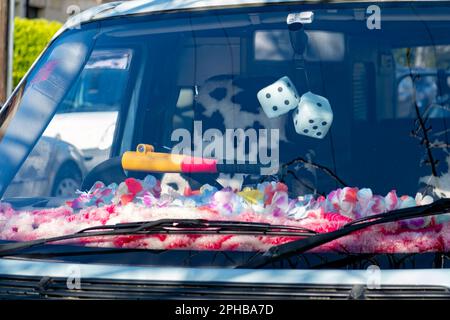 A close up of the front of a camper van showing a decorated dashboard, fur seat covers and two furry fluffy dice hanging from the rear view mirror Stock Photo