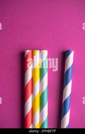 Detail of four colorful paper straws on a purple background Stock Photo