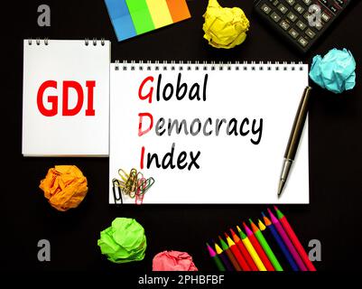 GDI global democracy index symbol. Concept words GDI global democracy index on white note on beautiful black background. Pencil and pen. Business and Stock Photo