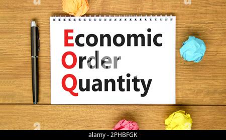 EOQ economic order quantity symbol. Concept words EOQ economic order quantity on white note on beautiful wooden table wooden background. Pen. Business Stock Photo