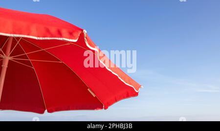 Umbrella Beach Background. Red Beach Umbrella on the Background of the Blue. Beach Landscape. Marine Background. Colorful summer Design. Preparation f Stock Photo