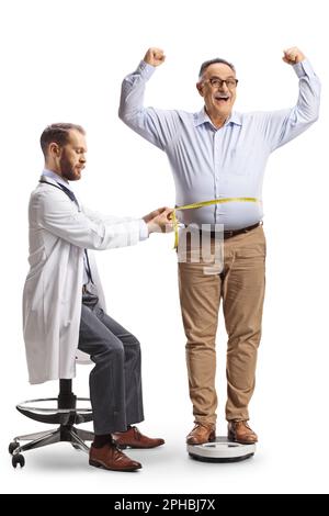 Mature man standing on a weight scale and doctor measuring his waist isolated on white background Stock Photo