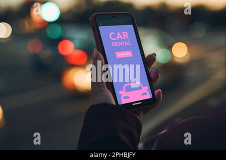 Woman renting car online using mobile app on smart phone. Person booking car using mobile application. Arranging ride in downtown city street. Car sha Stock Photo