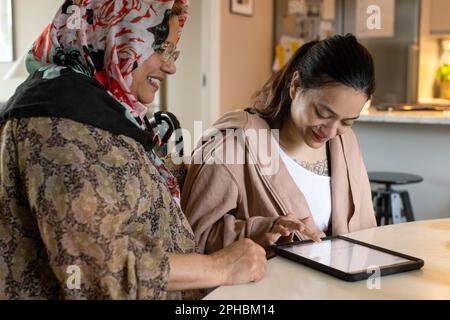 Woman with disability using tablet PC by mother at home Stock Photo