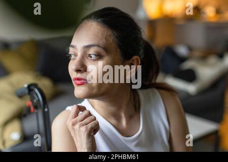 Thoughtful woman with paraplegia looking away at home Stock Photo