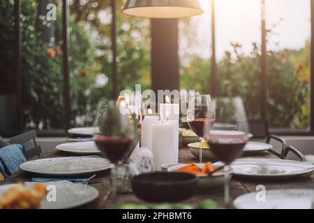 Illuminated candles with wineglasses on dining table Stock Photo
