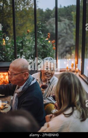 Senior female friends talking to each other during dinner party Stock Photo