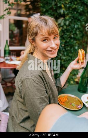Side view of smiling young woman sitting with food at restaurant Stock Photo