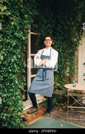 Happy male chef standing with arms crossed outside restaurant Stock Photo