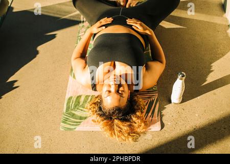 High angle view of woman exercising while lying on floor during yoga class Stock Photo