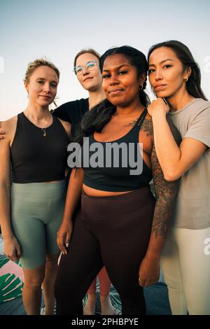Portrait of multiracial female friends standing together at retreat center Stock Photo