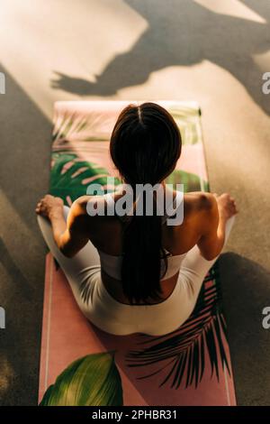 High angle view of woman meditating while sitting on exercise mat Stock Photo