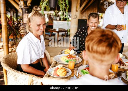 Happy woman having breakfast with family in resort during vacation Stock Photo