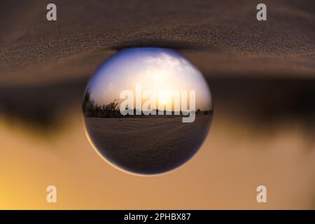 A scenic view of a rural landscape is seen in the reflection of a mirror, with a bright and clear sky in the background Stock Photo