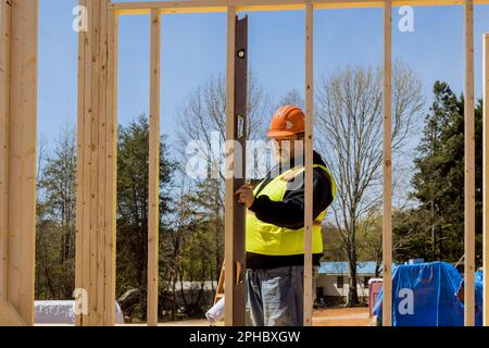 Using level an construction engineer checks leveling quality of wooden frames beams that are being constructed on worksite. Stock Photo