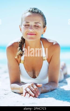 Happy young woman in swimsuit enjoying laying on sandy beach Stock Photo -  Alamy