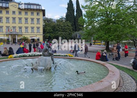 Citizens walking around the little mermaid fountain in the central square of Riva del Garda city Stock Photo