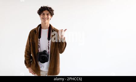 Photographers choosing it. Handsome young guy with digital camera pointing aside at free space, panorama Stock Photo