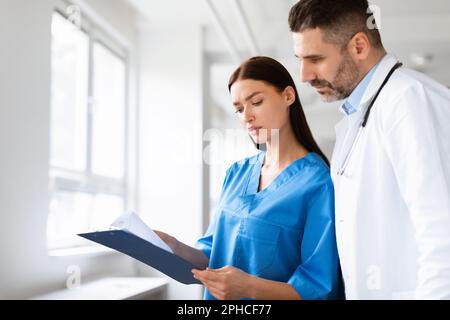 Team of doctors working together on patients file, analyzing report, having discussion in hospital office, copy space Stock Photo