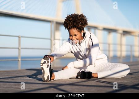 Motivated Young African American Woman In Sportswear Stretching Outdoors Stock Photo