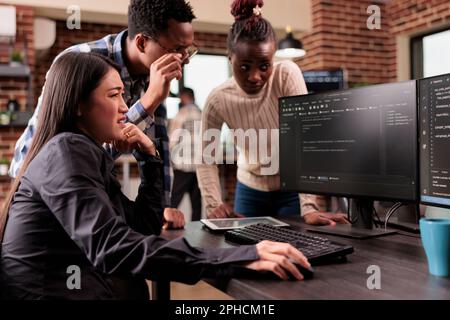 Diverse programming engineers talking about html script, looking at code on computer, working on server interface development. Tech enginners parsing cloud computing project with big data in it agency Stock Photo
