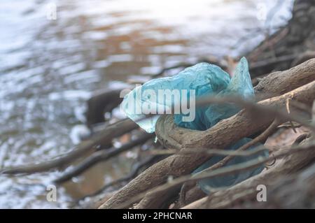 Plastic bag stuck on the edge of a river,concept of pollution of nature,garbage in nature,copy space on the left. Stock Photo