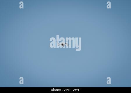 Drone flying in sky against blue background for copy space. Stock Photo