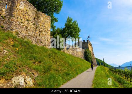 Woman Walking on a Walkway to a Castle and Vineyard in a Sunny Summer Day in Morcote, Ticino, Switzerland. Stock Photo