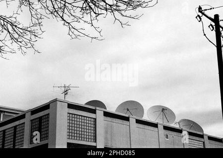 A row of satellite dishes line the roof of a commercial building on Main St. against a dramatic sky in Stoneham, Massachusetts. The image was captured Stock Photo