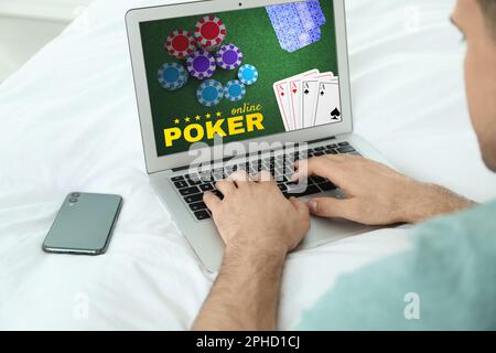 Man playing poker on laptop indoors, closeup. Casino online Stock Photo