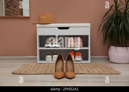 Shelving unit and stylish shoes on floor in hall Stock Photo