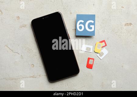 6G technology, Internet concept. Smartphone with blank screen and SIM cards on light table, flat lay Stock Photo