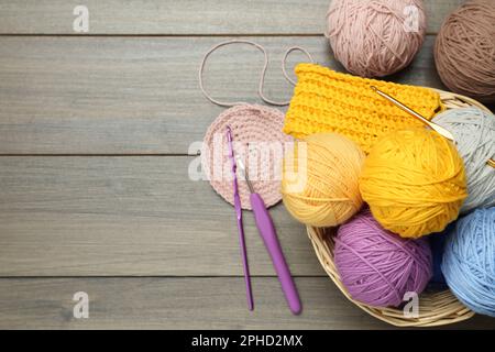 Clews, knitting and crochet hooks on wooden table, flat lay. Space for text Stock Photo