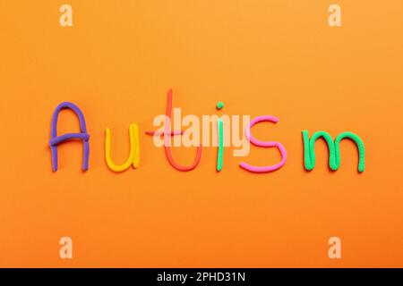 Word Autism made with colorful plasticine on orange background, flat lay Stock Photo